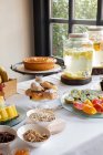 Vista laterale della cena festiva con gustosi prodotti da forno a base di frutta e raffinate sponde di limonata su tavola decorate con fiori lilla — Foto stock