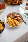 Сверху вкусное блюдо из бекона и тушеных яиц на тарелке с вилкой на красивом завтракающем столе — стоковое фото