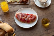 De cima de torrada espanhola saborosa com tomate e bacon para café da manhã na mesa de madeira — Fotografia de Stock