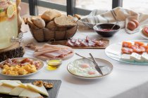 Von oben Blick auf die gemütliche Tischdekoration bestehend aus Spiegeleiern und Speck Lachskäse Mehl und Backwaren zu Hause — Stockfoto