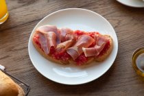 Von oben leckerer spanischer Toast mit Tomate und Speck zum Frühstück auf Holztisch — Stockfoto
