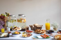 Von oben von appetitlichen Sitztisch zum Frühstück mit Bäckerei Meeresfrüchte Sandwiches Eier und Orangensaft im stilvollen Speisesaal — Stockfoto