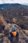 Вид сверху на неузнаваемую женщину, сидящую на скалах на краю скалы с живописным видом — стоковое фото