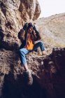Ruhige Frau in warmer Kleidung sitzt auf Bergklippe — Stockfoto
