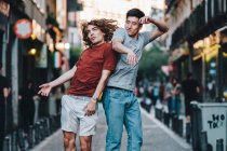 Vista lateral de homens multirraciais excitados pulando juntos e batendo de volta na rua da cidade — Fotografia de Stock