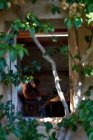 Ansichten von Baumzweigblättern eines Arbeiters in Schutzbrille und Handschuhen beim Schneiden von Metall mit einem Schleifer mit Funkenflug während der Arbeit in der Werkstatt — Stockfoto