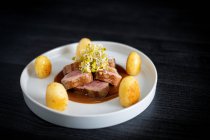 Dall'alto delizioso filetto Duroc con soia allo zenzero arancione e patate in piatto bianco su sfondo nero — Foto stock