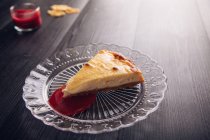 Baked cheesecake with red jam in glass plate — Stock Photo