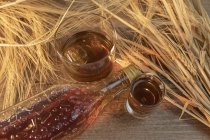 Bottiglia con bevanda e spari sul tavolo su tavolo rustico — Foto stock
