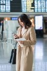 Frau nutzt Smartphone am Flughafen — Stockfoto