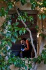 Вид с ветки дерева листья профессионального мастера в защитной маске паяльник металла во время работы в небольшой мастерской — стоковое фото