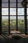 Lounge-Bereich mit rundem Holztisch und Metallstuhl gegen hohe Fenster mit Gitter im Kontrastlicht in der Bibliothek texas — Stockfoto