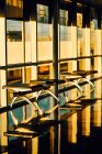 Banco de metal con asientos negros de cuero a lo largo de la pared de cristal en el pasillo soleado del aeropuerto de Texas - foto de stock