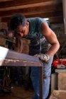 Мастер средних лет в защитных перчатках, маркирующий металлический лист во время работы в мастерской — стоковое фото