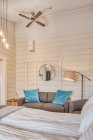 Комфортабельная спальня с белыми деревянными стенами и большой мягкой кроватью с уютным диваном рядом с горящим полом — стоковое фото