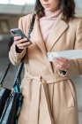 Обрезанное изображение женщины с помощью смартфона в аэропорту — стоковое фото