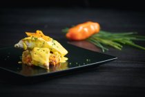 Corvina with yellow pepper sauce in black plate — Stock Photo