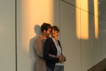 Geschäftsmann umarmt Freundin, während er nach Feierabend vor modernem Gebäude steht — Stockfoto