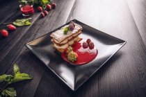 Crema de diflomato y strudel de fruta roja en elegante plato negro - foto de stock