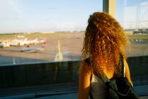 Visão traseira da mulher elegante encaracolado com mochila observando campo com aviões no aeroporto do Texas — Fotografia de Stock