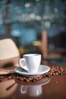 Tazze di gustosa bevanda calda in composizione con cappello e chicchi di caffè sul tavolo di legno — Foto stock