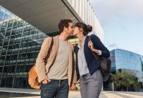 De baixo feliz casal colegas beijando uns aos outros, enquanto em pé fora edifício moderno na rua da cidade após o trabalho — Fotografia de Stock