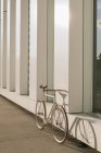 Bicicleta estacionada na calçada perto da parede do edifício contemporâneo no dia ensolarado na rua da cidade — Fotografia de Stock