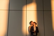 Businessman embracing and kissing girlfriend while standing outside modern building after work — Stock Photo