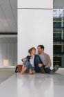 Мужчина-менеджер обнимает и целует подружку, сидя снаружи офисного здания на городской улице после работы — стоковое фото