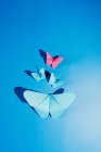 Fragile butterflies made of paper and attached to blue silk fabric — Stock Photo