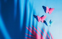 Farfalle fragili di carta con ombra di foglie di palma attaccate al tessuto di seta blu — Foto stock