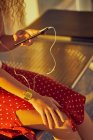 Зображення жінки в навушниках, яка слухає музику за допомогою мобільного телефону, коли холоне на металевій лавці в аеропорту Техасу. — стокове фото