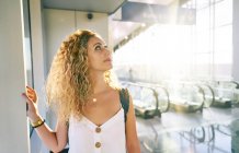 Charming curly woman with backpack walking along light spacious room of airport in Texas — Stock Photo