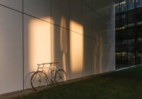 Vélo stationné sur le trottoir près du mur du bâtiment contemporain par une journée ensoleillée sur la rue de la ville — Photo de stock
