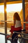 Женщина, сидящая на металлической скамейке в стеклянном коридоре аэропорта в Техасе — стоковое фото