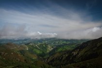 Perspektivische erstaunliche Aussicht auf grüne Hügel mit dichtem Wald und Wiesen unter dicken, üppigen Wolken in Asturien bei sonnigem Tag — Stockfoto