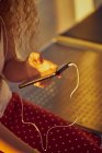 Immagine ritagliata di donna in auricolare ascoltare musica con il telefono cellulare mentre si raffredda sulla panchina metallica in aeroporto del Texas — Foto stock