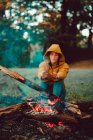 Traveling woman warming hands near campfire on forest glade — Stock Photo