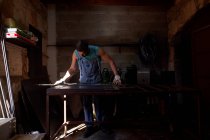 Мастер средних лет в защитных перчатках, маркирующий металлический лист во время работы в мастерской — стоковое фото