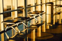 Banco de metal com bancos pretos de couro ao longo da parede de vidro no corredor ensolarado do aeroporto no Texas — Fotografia de Stock