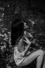 Застенчивая чувственная женщина, сидящая на камне в лесу — стоковое фото