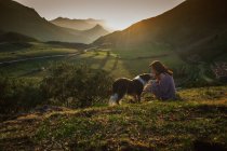 Дорослий турист з собакою проти зеленої лісової долини під ясним небом влітку — стокове фото