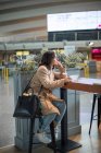Frau sitzt am Flughafen und nutzt Smartphone — Stockfoto