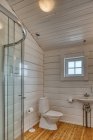 Élégant intérieur minimaliste salle de bains avec plancher en bois et murs blancs avec petite fenêtre à la maison — Photo de stock