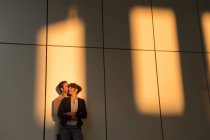 Бізнесмен приймає і цілує дівчину, стоячи за межами сучасної будівлі після роботи — стокове фото