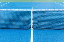 Detalle de pista de tenis al aire libre azul y verde con red negra . - foto de stock
