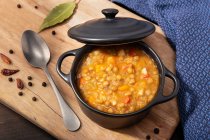 Traditional spanish lentil soup with legumes in black casserole pot on table. — Stock Photo