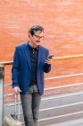 Alter Mann steht mit Gepäck da und spricht auf Smartphone — Stockfoto