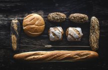 Flache Lage des Goldsortiments hausgemachtes Brot auf dunklem Holzgrund — Stockfoto