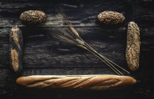 Disposición plana de oro surtido pan casero sobre fondo de madera oscura - foto de stock